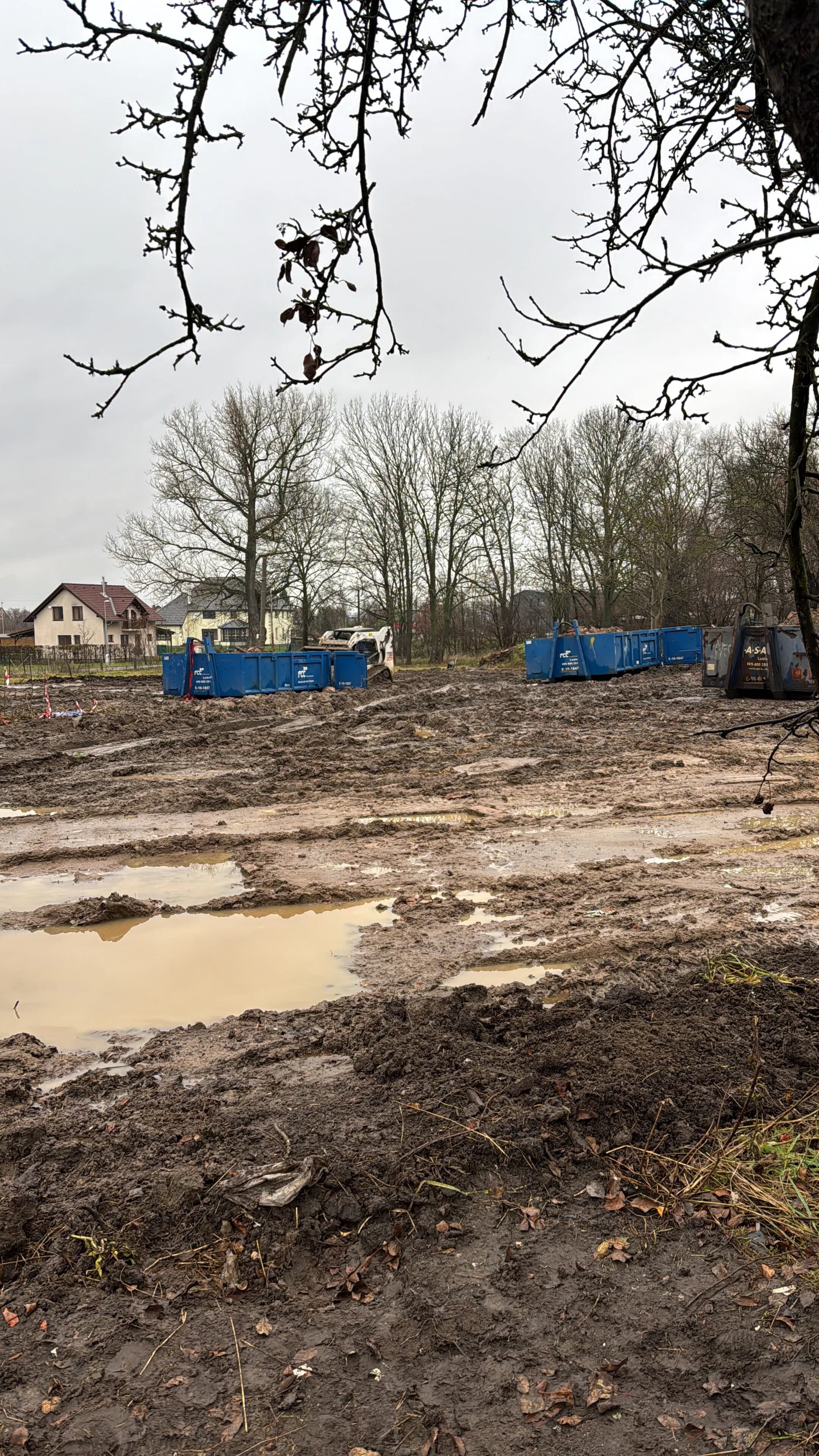 Pozemek po demolici s přistavenými kontejnery na odpad