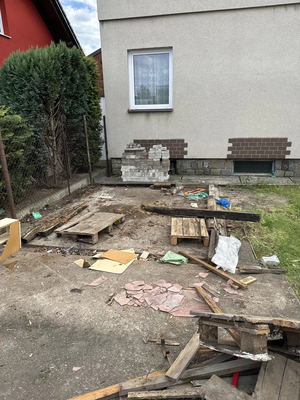 Místo po odstraněné kůlně, dřevo a palety připravené k odvozu
