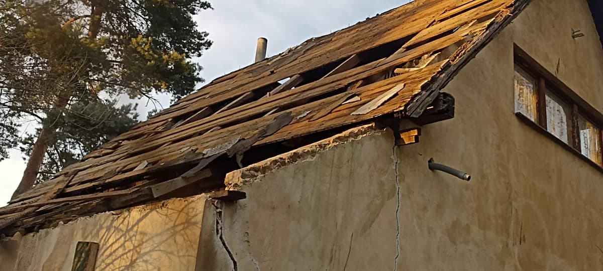 Poškozená dřevěná střecha staré stavby před demolicí
